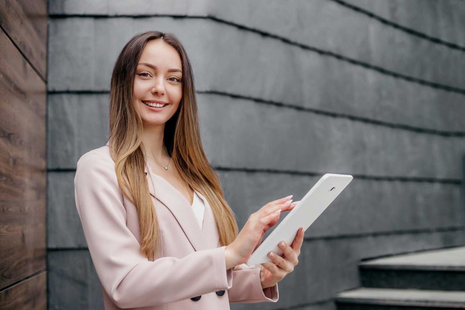 smiling caucasian businesswoman standing and holding a tablet